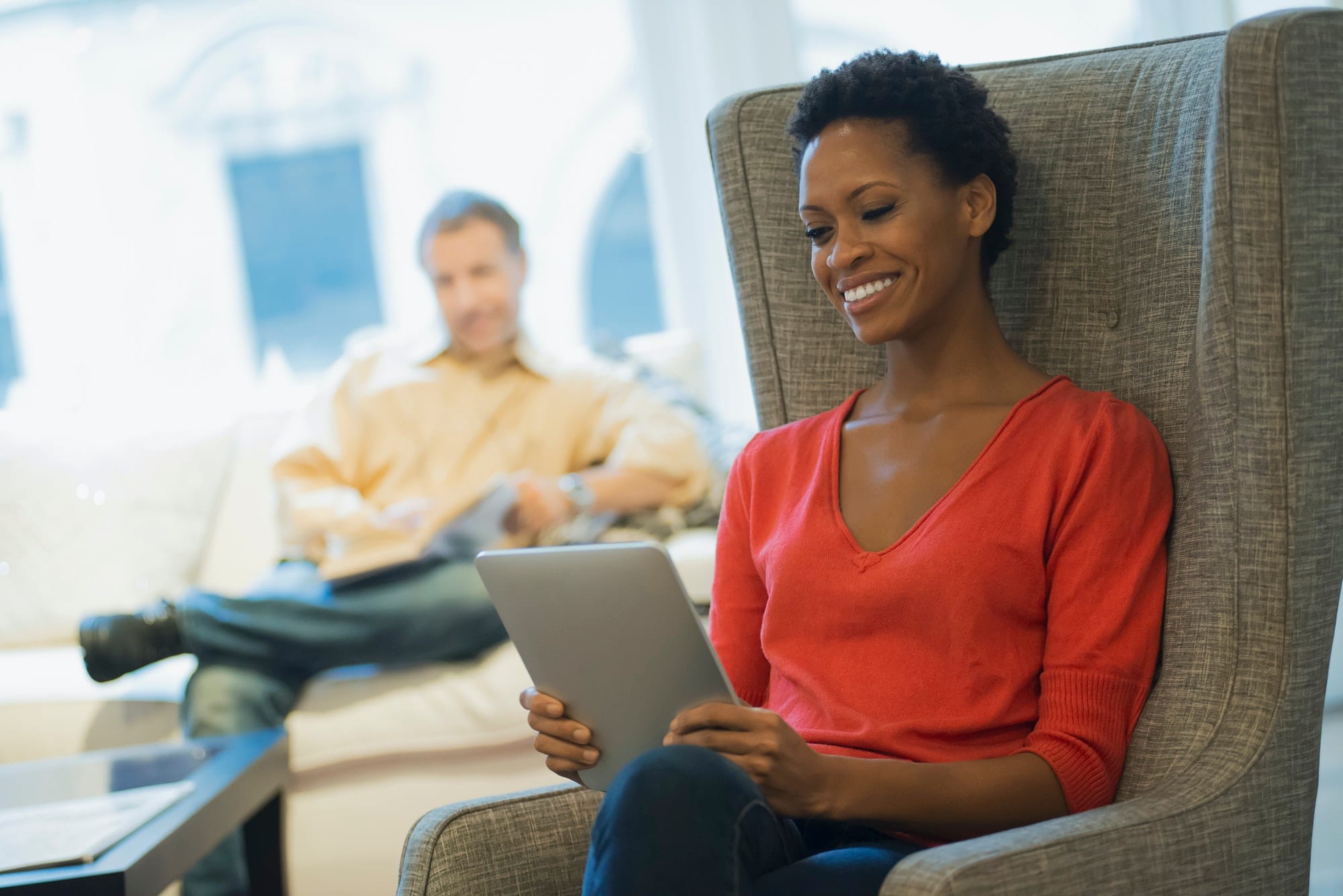 Couple relaxing at home reading, woman with tablet Couple relaxing at home reading, woman with tablet