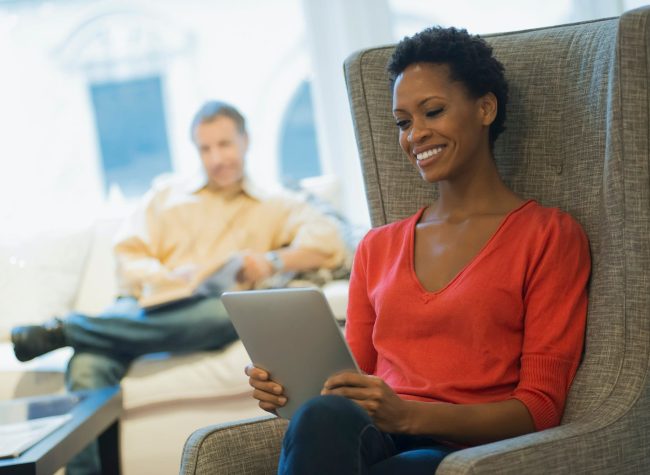 Couple relaxing at home reading, woman with tablet Couple relaxing at home reading, woman with tablet